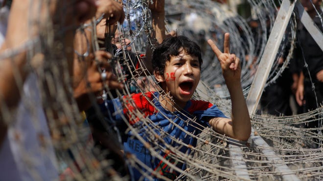 Egyptian boy peers out of barbed wire.jpg